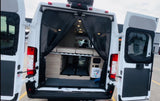 Rear of a white camper van RV rental, doors open to reveal an elevated bed, under-bed storage, and a protective mesh screen.