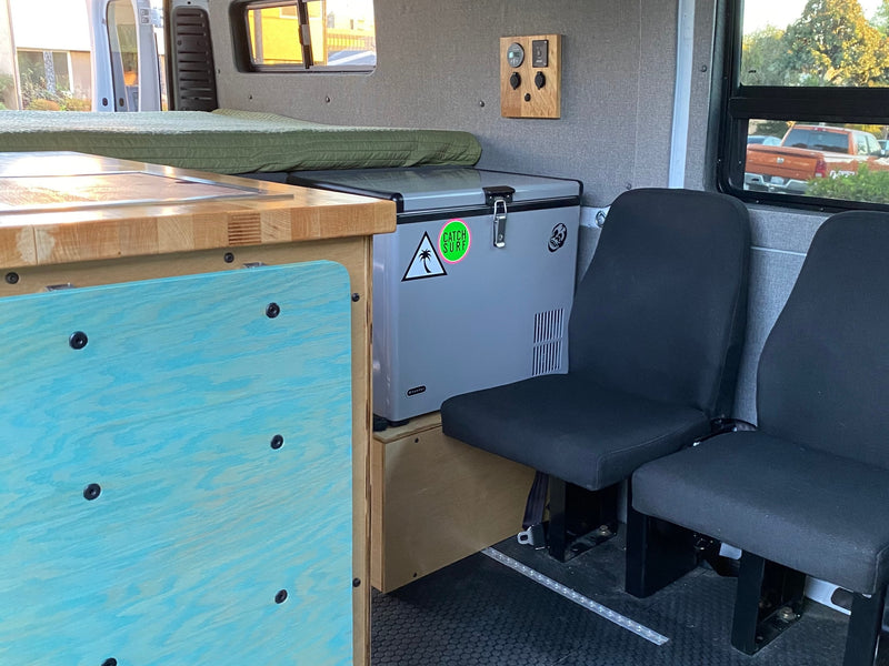 RV rental: Camper van interior with cozy bed, portable fridge, wooden counter, and passenger seating. — photo 14