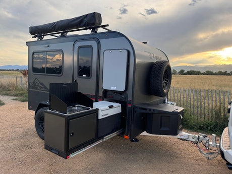 This RV rental camper features an outdoor kitchen, rooftop awning, and rugged tires, perfect for your next outdoor adventure.