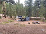 Escapod TOPO towed to a forested campsite with awning extended