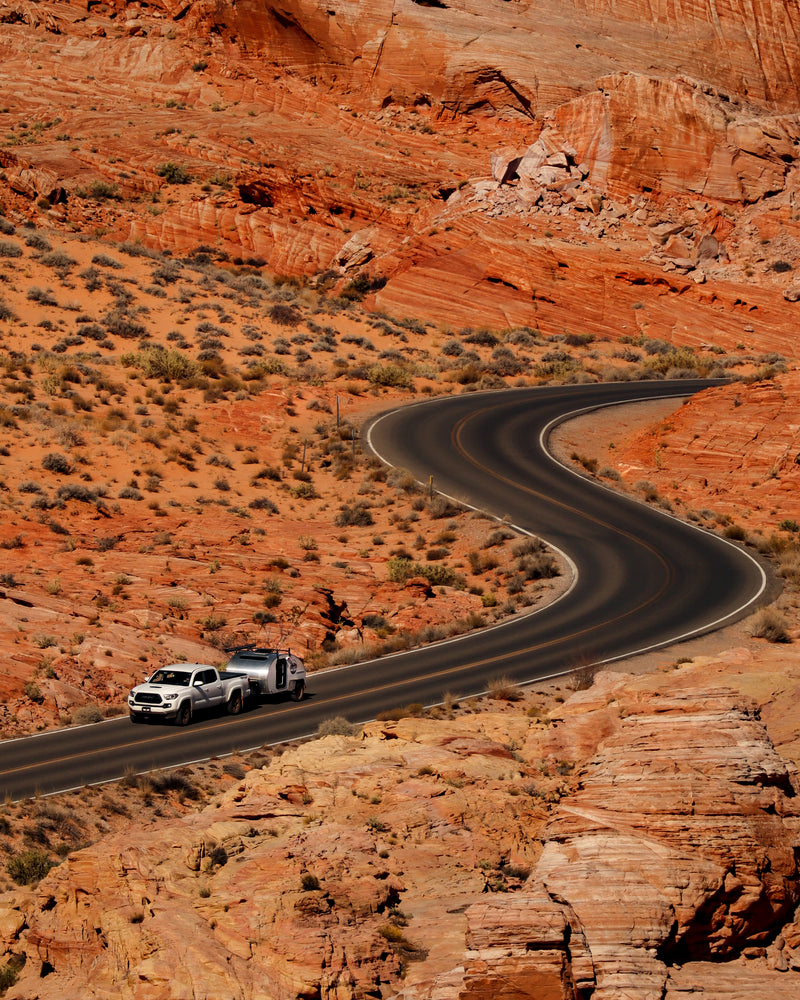 A white truck tows an RV rental through stunning red rock desert on a winding road, ideal for scenic drives and adventures. — photo 7
