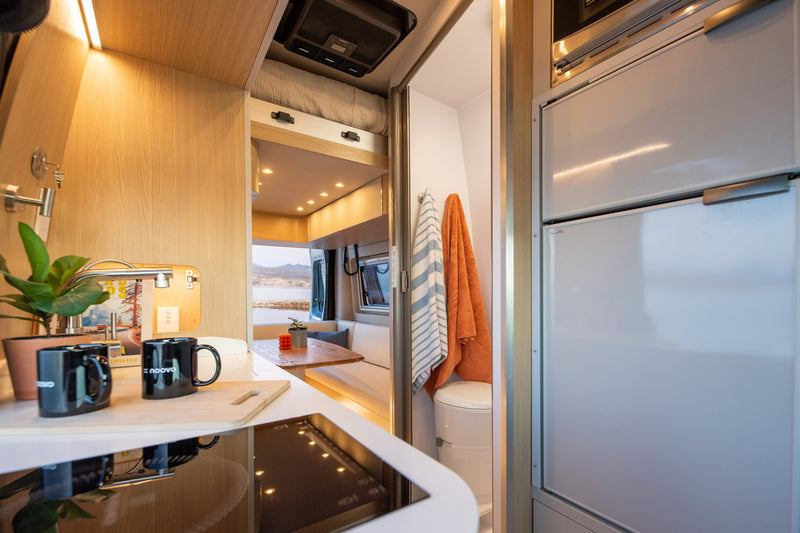 A full view of a modern rv rental interior, showing a kitchen, dining area with lake view, bed, and bathroom. — photo 4