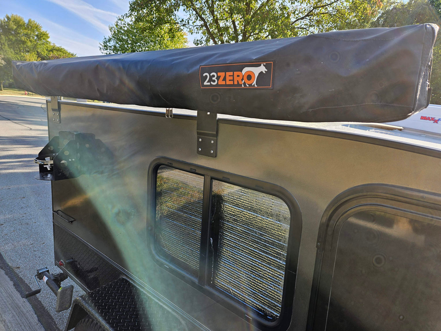 Side of a compact RV rental, showcasing a 23ZERO awning and window, perfect for outdoor camping adventures.