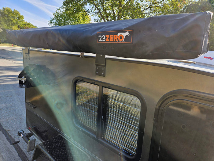 Side of a compact RV rental, showcasing a 23ZERO awning and window, perfect for outdoor camping adventures.