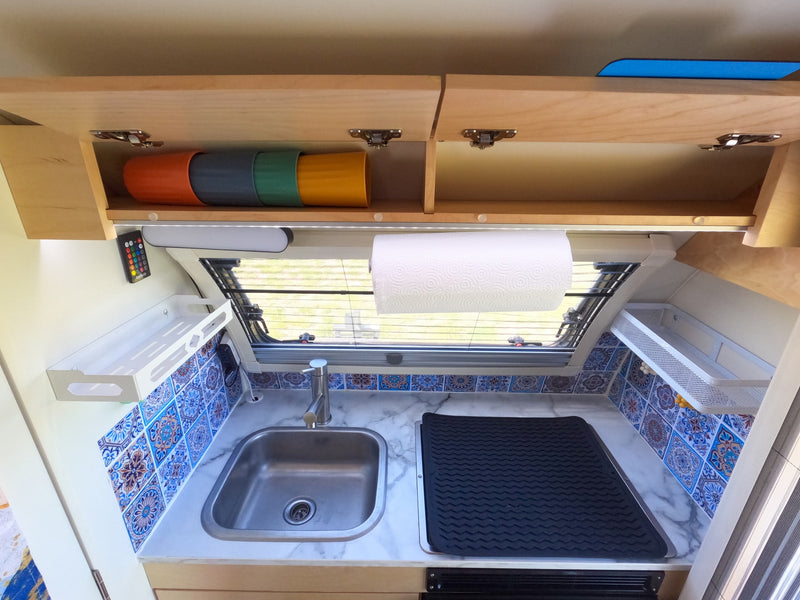 Compact RV rental kitchen with sink, tiled backsplash, and clever storage solutions, ideal for travel adventures. — photo 15