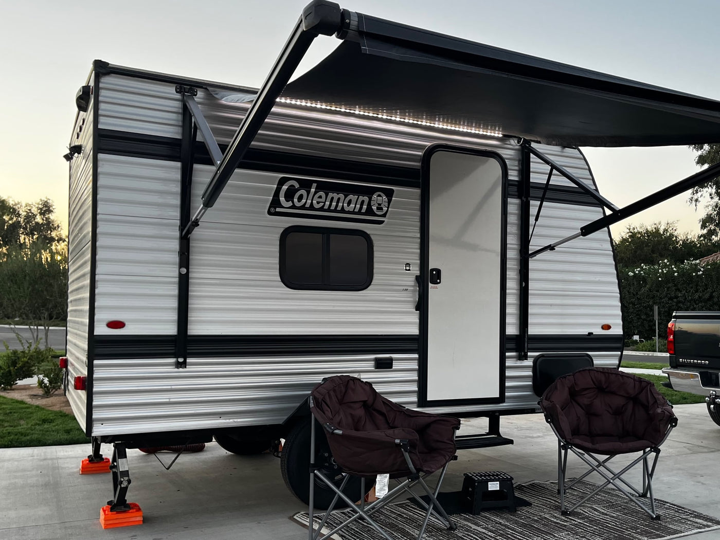  and stabilizer jacks at a campsite.|Cozy rv rental night. Illuminated Coleman travel trailer with awning lights — photo 4