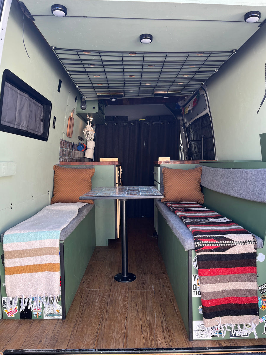 Inviting camper van interior with a dining area and compact kitchen, great for an RV rental and road trips.