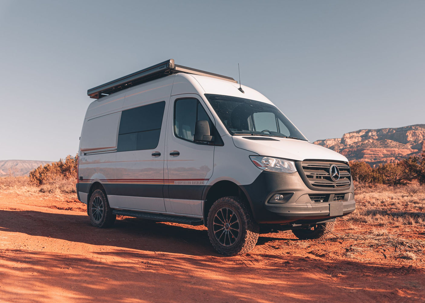 White Mercedes Sprinter RV rental van on red dirt road. Off-road capable, perfect for desert adventure.