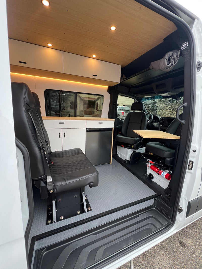 Clean, modern RV rental interior featuring a custom kitchen with fridge, cozy seating, wood ceiling, and safety equipment. — photo 9