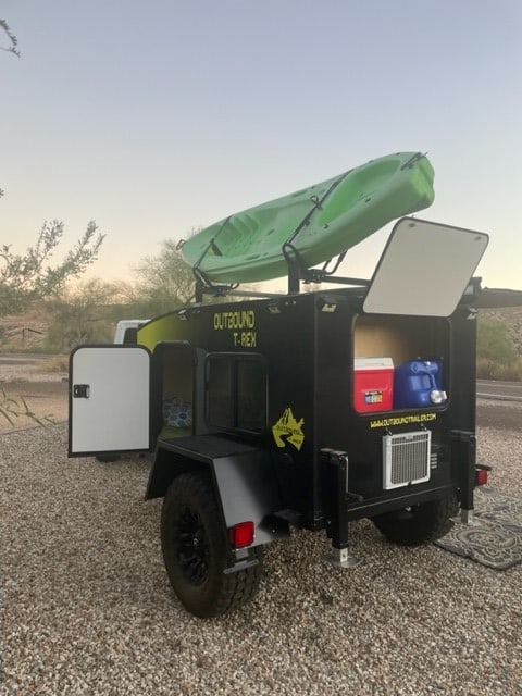  and chairs on gravel.|A white Jeep Wrangler tows an Outbound T-Rex off-road overland camper. Ideal for an adventurous RV rental trip.|RV rental setup with a black Outbound T-Rex teardrop trailer — photo 4