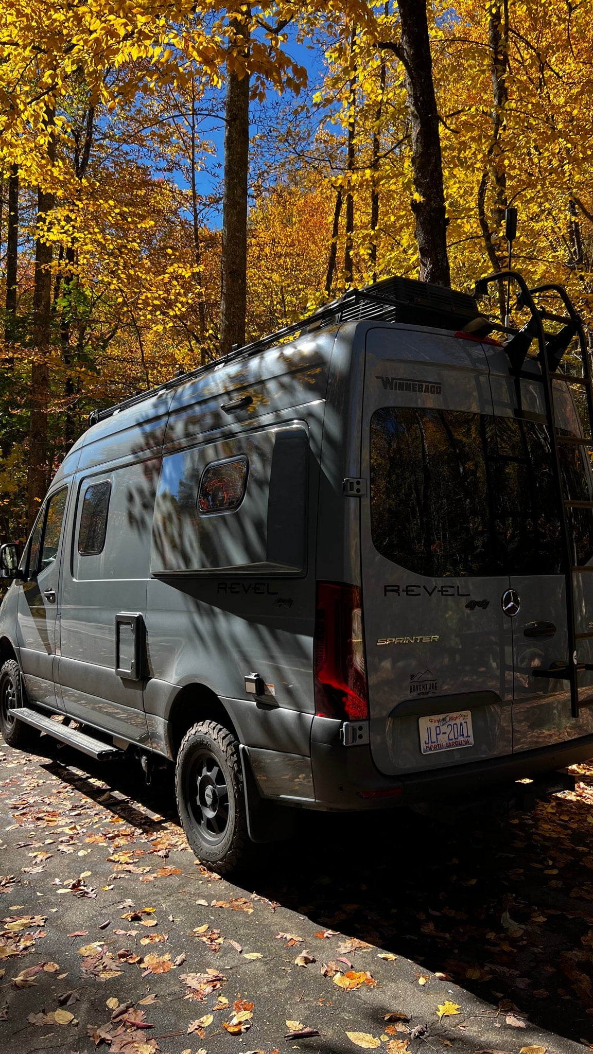 Grey Winnebago Revel RV rental van parked under bright yellow autumn leaves. Perfect for fall adventures. — photo 5