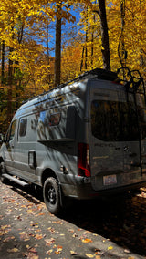 Grey Winnebago Revel RV rental van parked under bright yellow autumn leaves. Perfect for fall adventures.