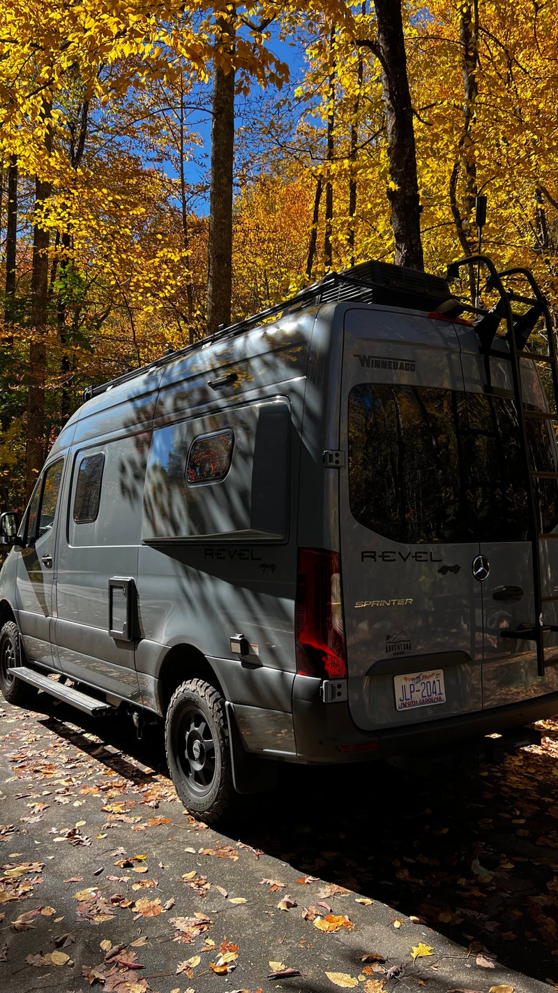 Grey Winnebago Revel RV rental van parked under bright yellow autumn leaves. Perfect for fall adventures. — photo 5