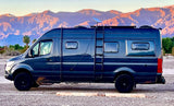 A custom dark camper van, ready for an rv rental road trip, parked against a breathtaking backdrop of sunlit desert mountains.