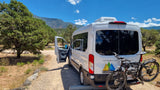 An RV rental camper van with bikes parked in a scenic mountain area, ready for adventure.