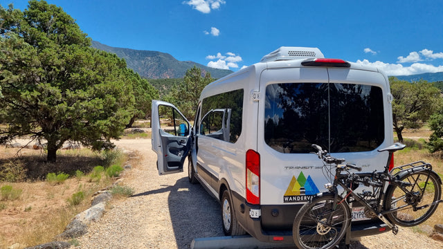 An RV rental camper van with bikes parked in a scenic mountain area, ready for adventure.