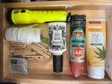 RV rental drawer packed with essentials: flashlight, string, clothespins, Advil, Poo-Pourri, bug spray, and lotion.