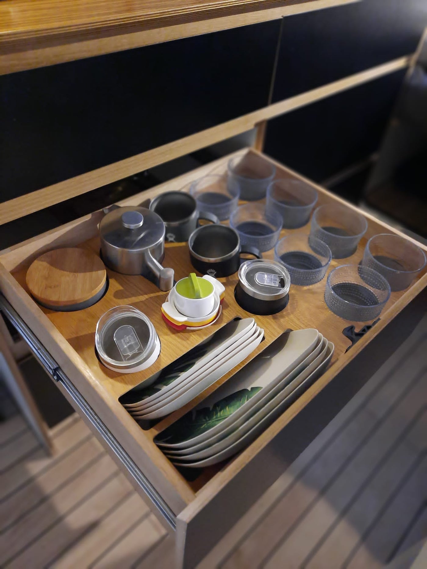 Compact kitchen essentials in an RV rental drawer: cups, plates, & a teapot, neatly stored for travel. — photo 9