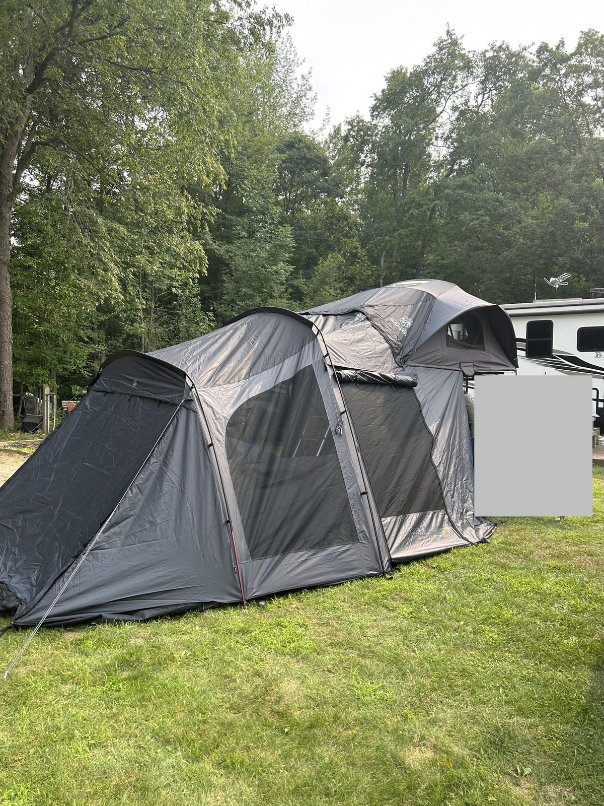 Full camp setup on grass with the Annex Plus ground room zipped onto the rooftop tent, showing the annex walls, mesh door panel and the tent open above on the vehicle — photo 3