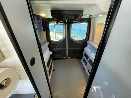 Explore with this RV rental! Inside a camper van, enjoy a water view from the rear windows, with modular interior and storage.