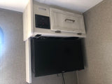 RV rental interior with a mounted TV, Fusion entertainment system, and light wood storage cabinet.