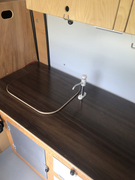 RV rental kitchenette showcasing a dark counter, faucet, and designed space for a sink. Efficient and compact camper.