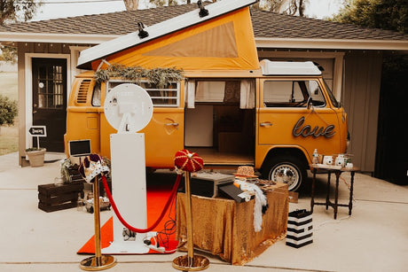 A cheerful yellow VW rv rental van set up as a photo booth with props and red carpet for events.