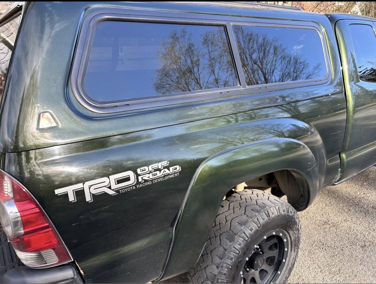 Green Toyota Tacoma TRD Off Road pickup truck with a matching camper shell, ready for an rv rental adventure.