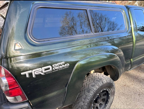 Green Toyota Tacoma TRD Off Road pickup truck with a matching camper shell, ready for an rv rental adventure.