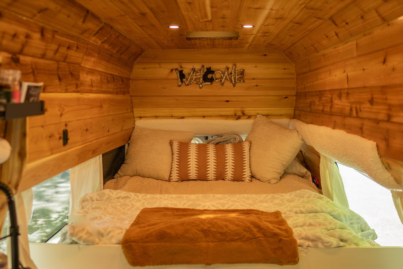  and a plush trim.|Cozy RV rental interior featuring a wood-paneled bedroom with a "WELCOME" sign and a scenic ocean and city view.|Stunning Golden Gate Bridge & SF Bay views from an RV rental. Cozy bed inside — photo 7