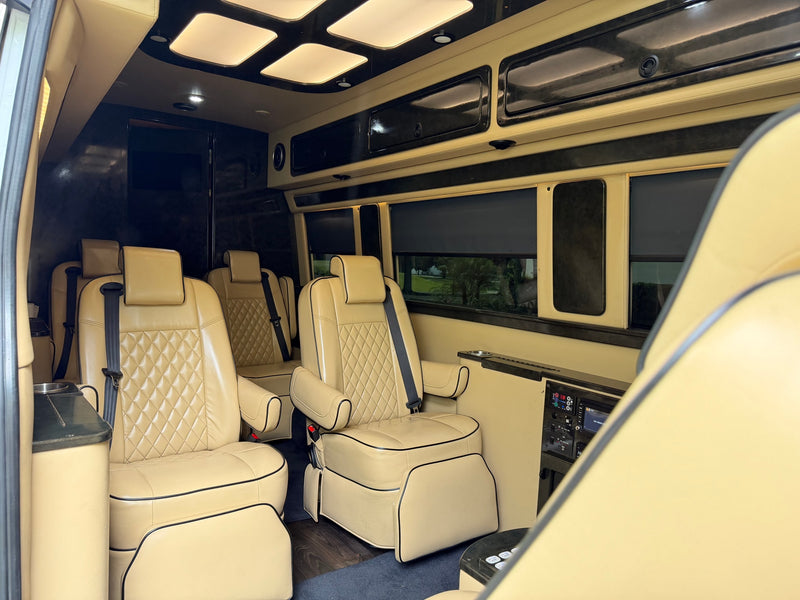 Plush RV rental interior features cream quilted leather captain's chairs, overhead lighting, and a passenger control panel. — photo 10