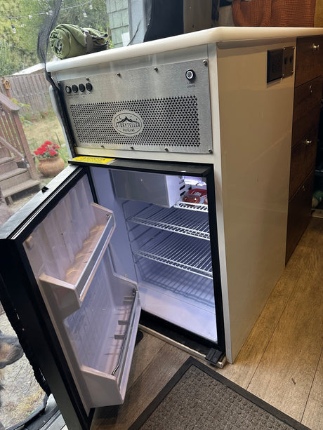 Inside an RV rental: an open refrigerator, control panel, and drawers for efficient camper storage. Ready for your trip!