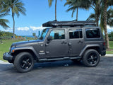This gray Jeep Wrangler with a rooftop tent, perfect for an RV rental, is ready for tropical off-road travel and beach camping.