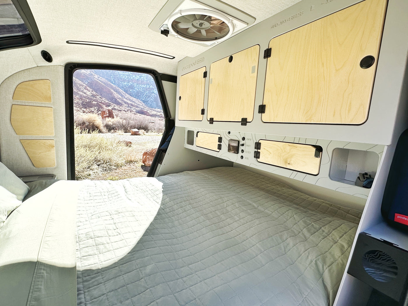 Inside a modern RV rental: a comfy bed, smart storage, and a large window framing a desert landscape. — photo 6