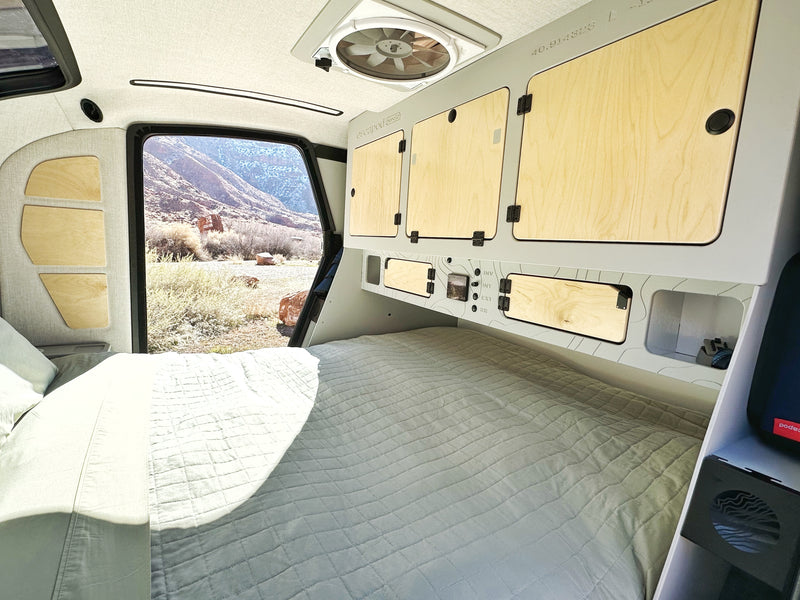 Inside a modern RV rental: a comfy bed, smart storage, and a large window framing a desert landscape. — photo 6