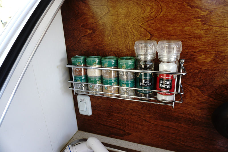 RV rental kitchen with organized spices on a rack: organic herbs, black peppercorns, & sea salt. Water pump switch below. — photo 4