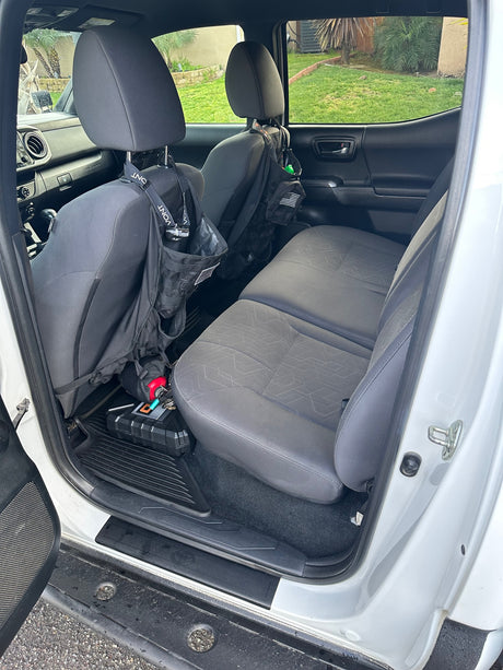Truck rear interior: folded seats reveal storage for bags, a case, and extinguisher. Ready for an RV rental adventure.