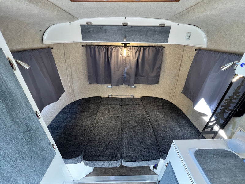 Cozy RV rental interior: a comfortable, modular bed, dark curtains, and light-toned walls. — photo 10