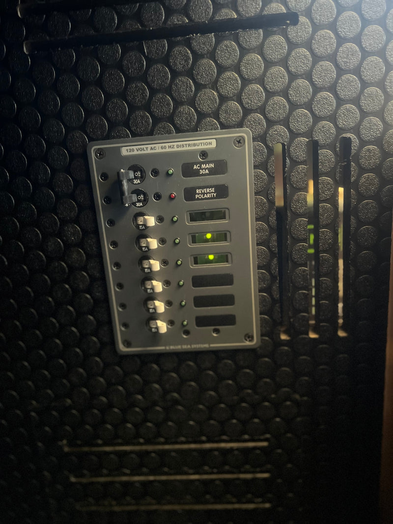 RV rental's 120V AC electrical distribution panel, with main and branch circuit breakers, status lights. Power on. — photo 18