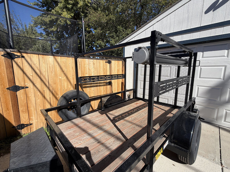 Looking down the open wood-plank deck from the rear quarter, showing the full overhead rack structure, the slotted accessory crossbar, the roller bar across the front and the mesh side panel — photo 7