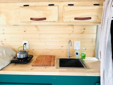 Experience convenient cooking in this RV rental's charming kitchenette, complete with sink, hot plate, and rustic wood accents.