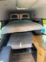 This RV rental shows a compact interior with stacked bunk beds and a built-in kitchenette.
