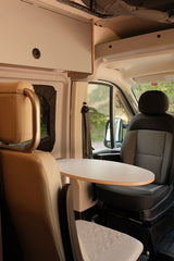 RV rental interior with a table between front swivel seats and overhead storage. Ideal for travel comfort.