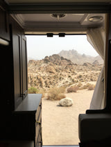 RV rental offers serene desert mountain views from its comfortable interior, a perfect mobile retreat in a rocky landscape.