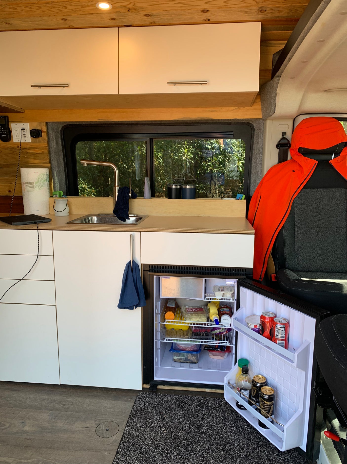 RV rental: a cozy converted van interior with a compact kitchen, open fridge, and a window view.