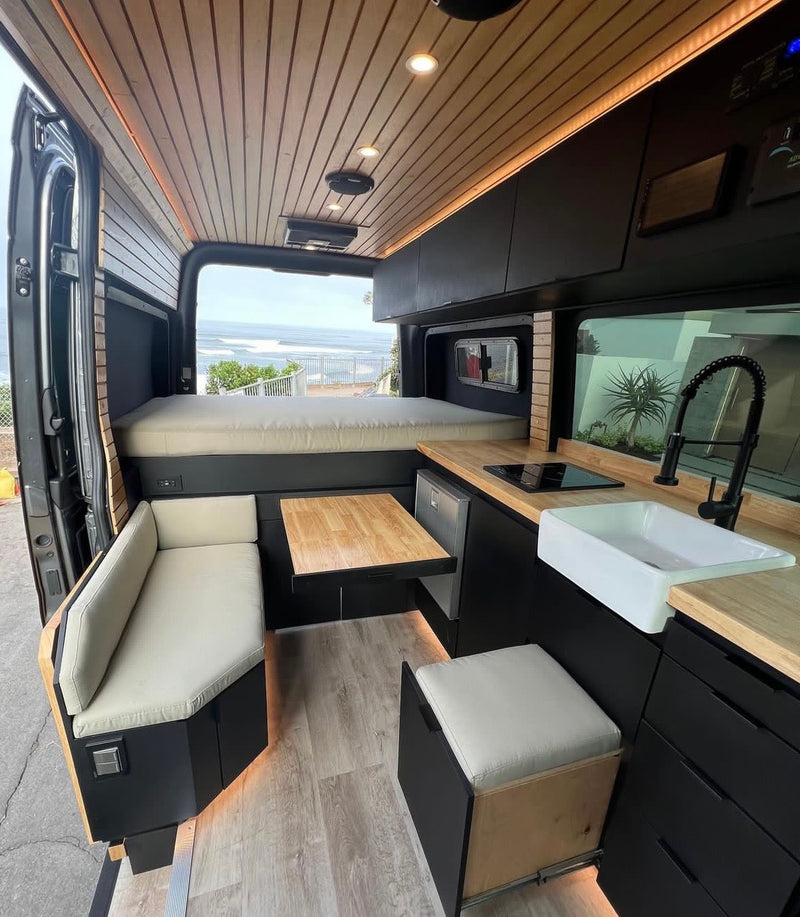 Step inside this custom RV rental camper van! A modern interior with wood accents, kitchen, bed, dining, and ocean view awaits. — photo 2