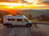 Experience breathtaking sunsets! This RV rental camper van is parked at Funnel Top overlook, surrounded by rolling mountains.