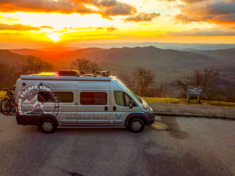 Experience breathtaking sunsets! This RV rental camper van is parked at Funnel Top overlook, surrounded by rolling mountains.