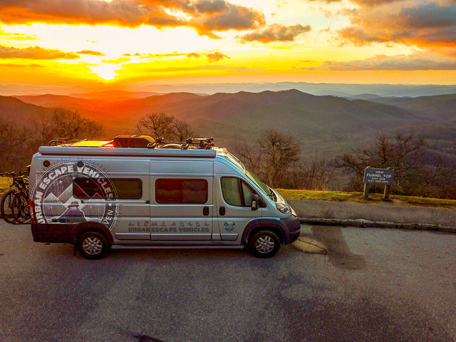 Experience breathtaking sunsets! This RV rental camper van is parked at Funnel Top overlook, surrounded by rolling mountains.