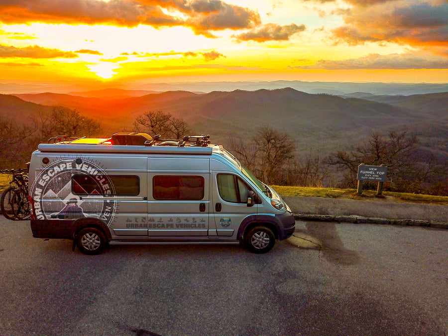 Experience breathtaking sunsets! This RV rental camper van is parked at Funnel Top overlook, surrounded by rolling mountains.